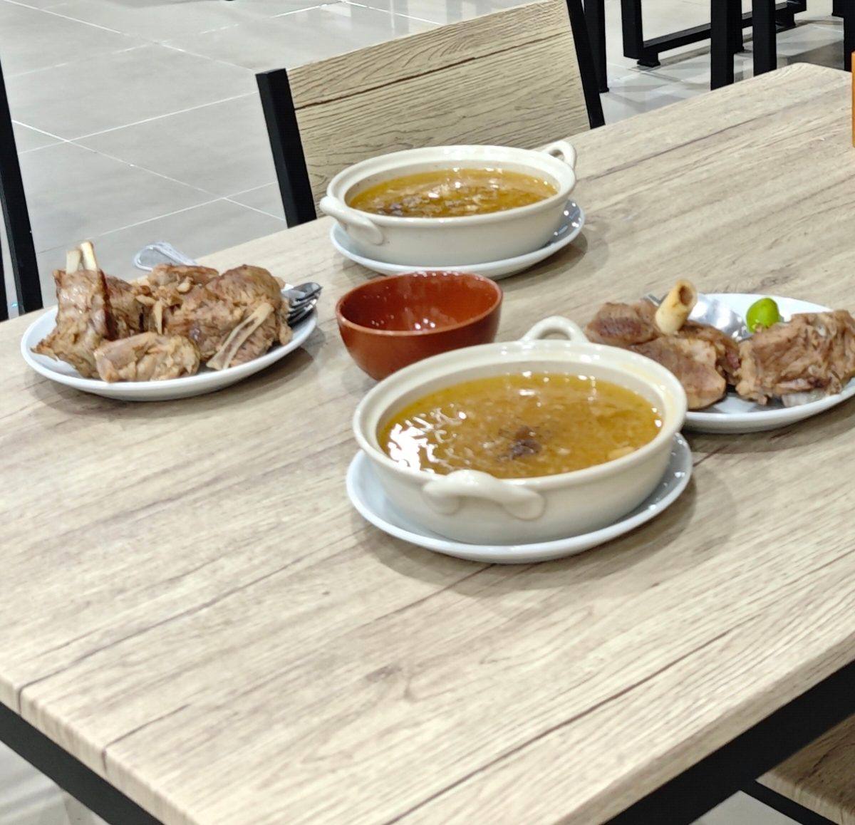 Cooked meat and soup dishes laid out on the table
